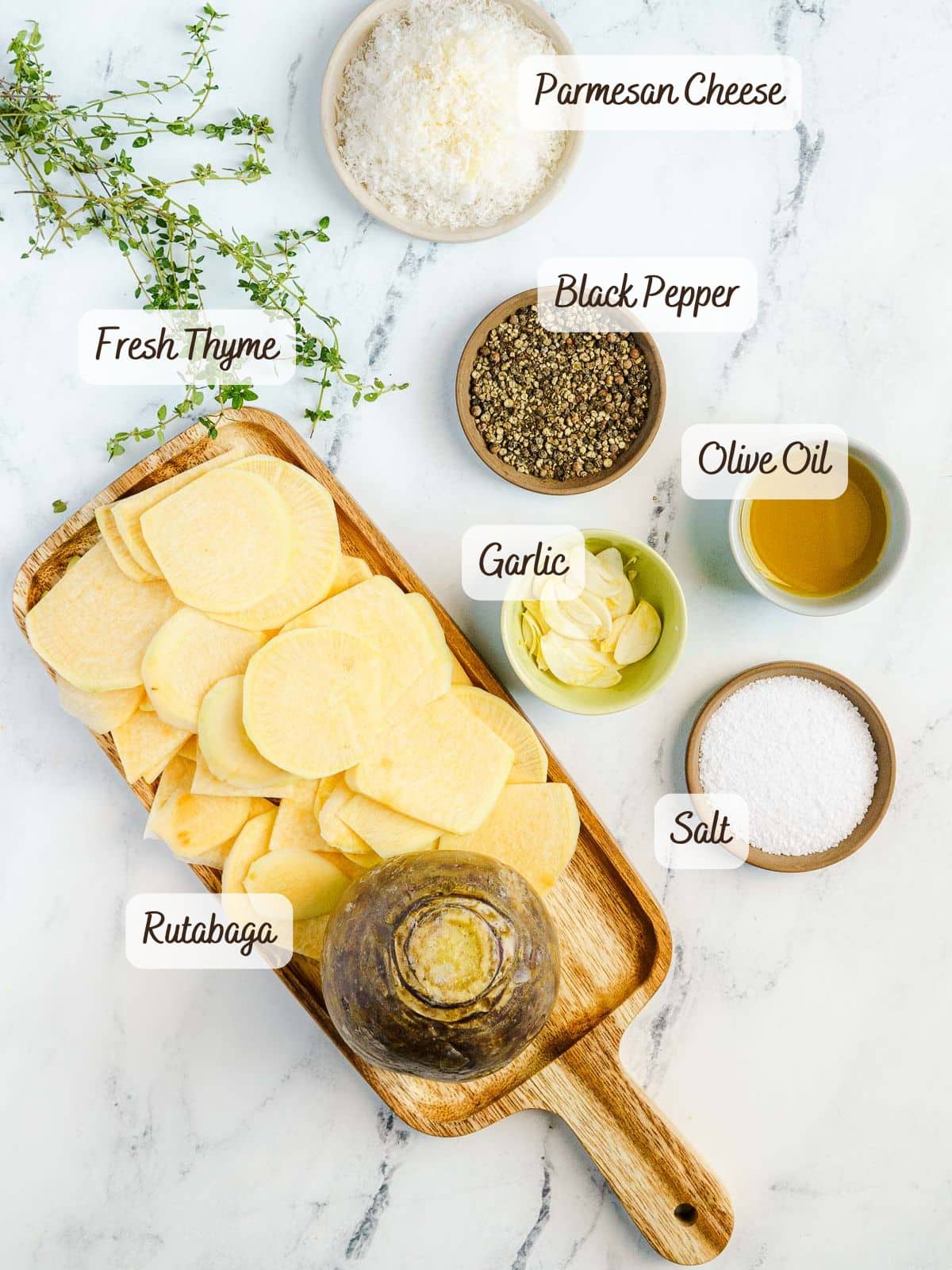 Sliced baked rutabaga, fresh thyme, grated parmesan, black pepper, olive oil, garlic, and salt arranged on a marble surface.