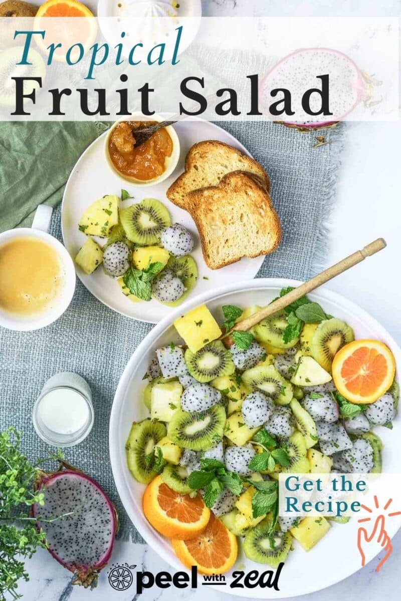 A bowl of tropical fruit salad with kiwi, pineapple, and chia seeds is accompanied by slices of bread and a cup of coffee. Dragon fruit adds a vibrant touch to the mix. "Tropical Fruit Salad" text and "Get the Recipe" button overlay the image.
