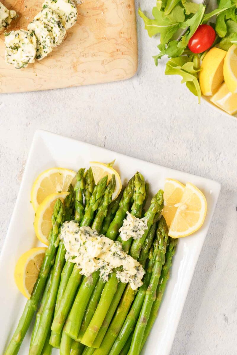 plate of steamed asparagus topped with compound butter