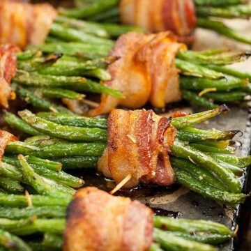 stack of greeen beans wrapped in bacon on sheet pan