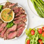 sliced bavette steak with sauce served with salad and asparagus