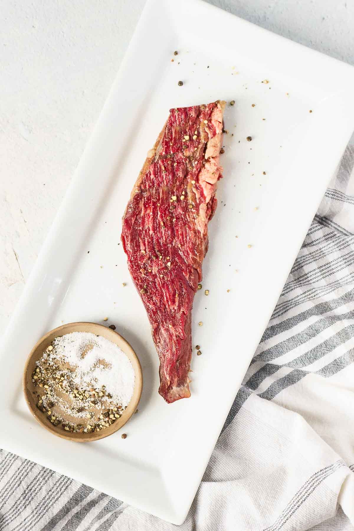 sprinkling steaks with salt and pepper