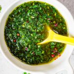 chimichurri in a bowl with a yellow spoon