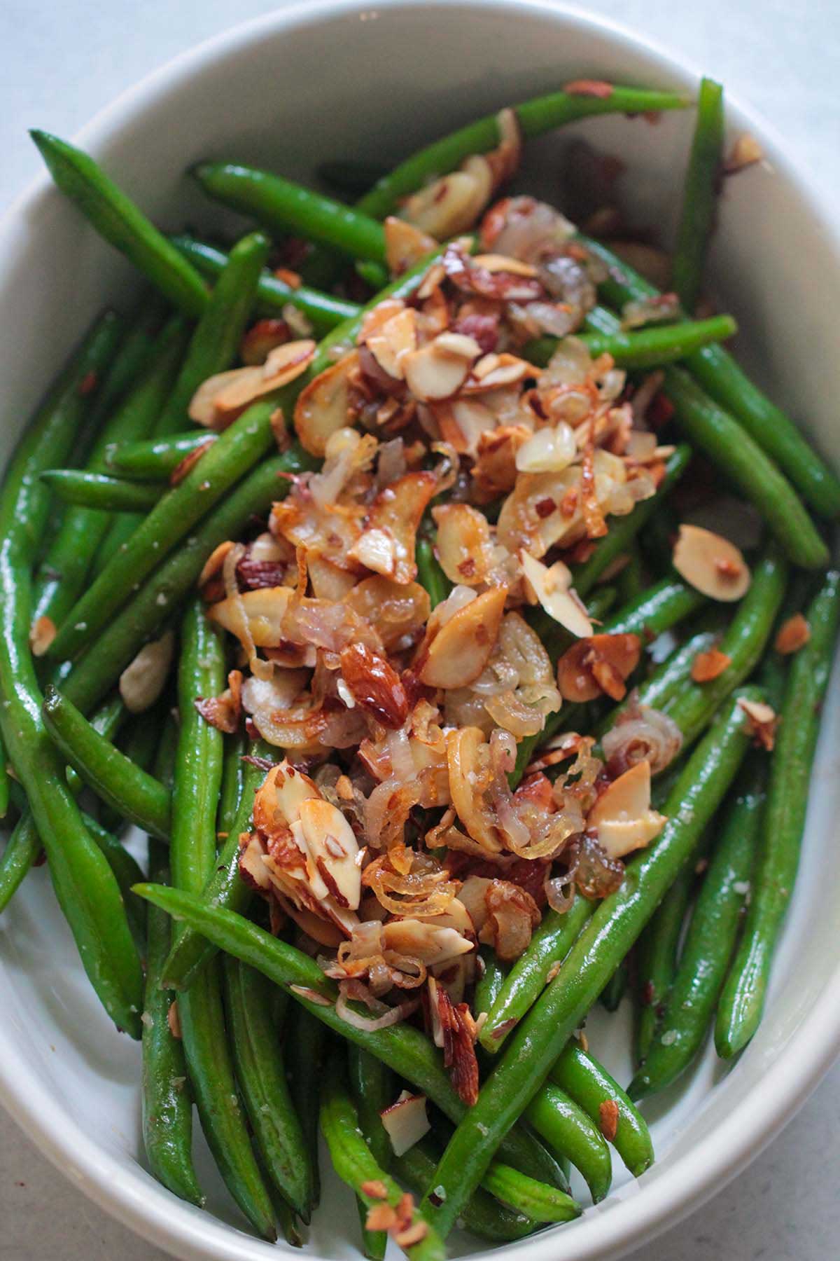 green beans with onions and almonds in a white bowl
