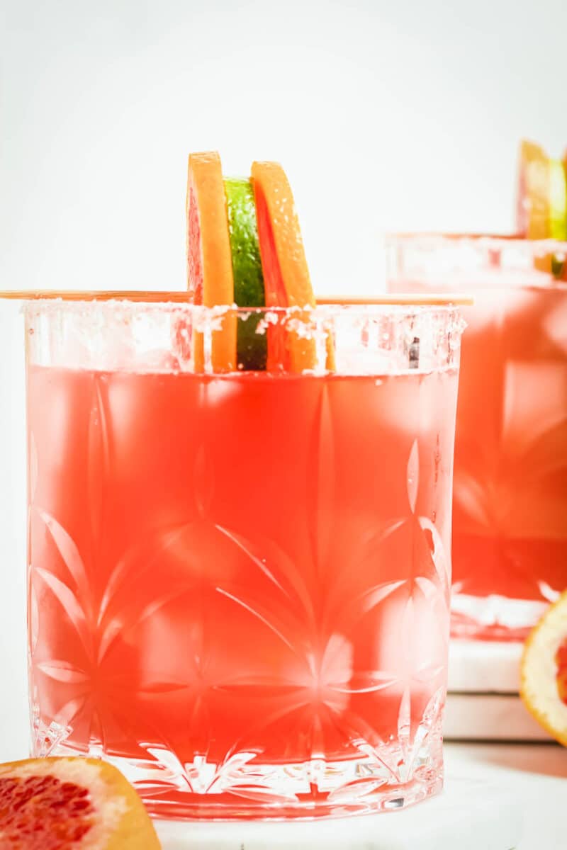 close up of pink margarita in a rocks glass with garnish.