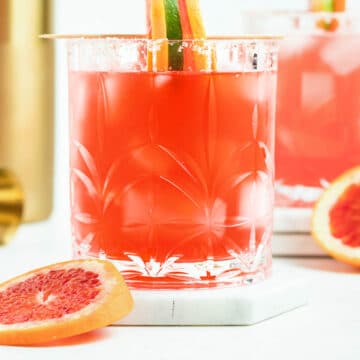 blood orange margarita recipe in a cocktail glass with orange wheel garnish.
