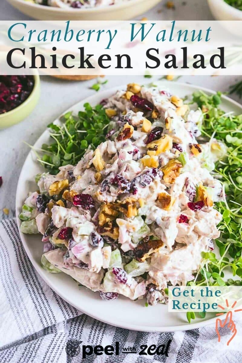 Plate of cranberry chicken salad on greens with nuts sprinkled on top. Text overlay reads "Cranberry Walnut Chicken Salad" and "Get the Recipe.