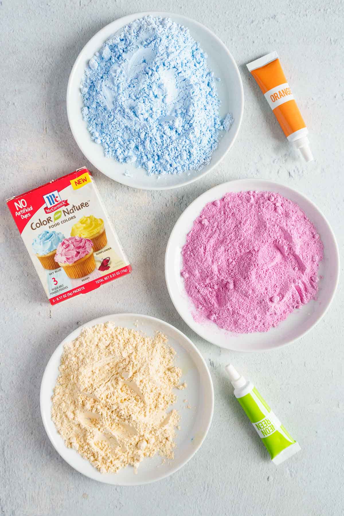 ingredients for powdered sugar plus blue powdered sugar and yellow powdered sugar on plates.