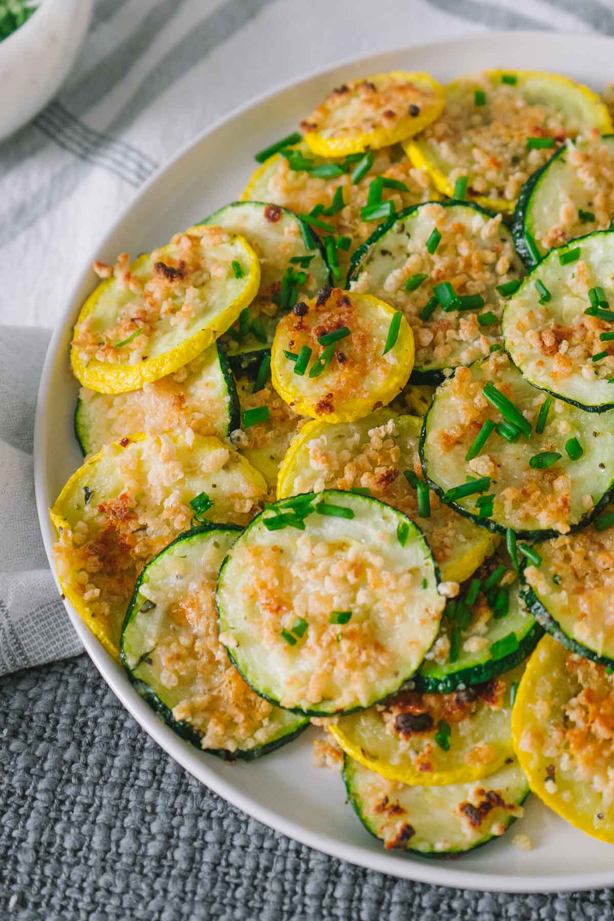 up close of roasted zucchini and squash slices topped with crispy parmesan cheese.
