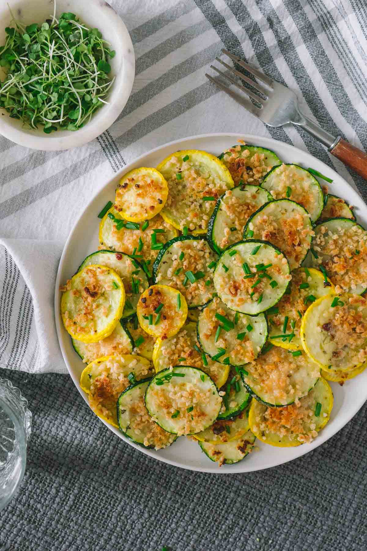 roasted sumemr squash and zucchini on a plate with chives. 