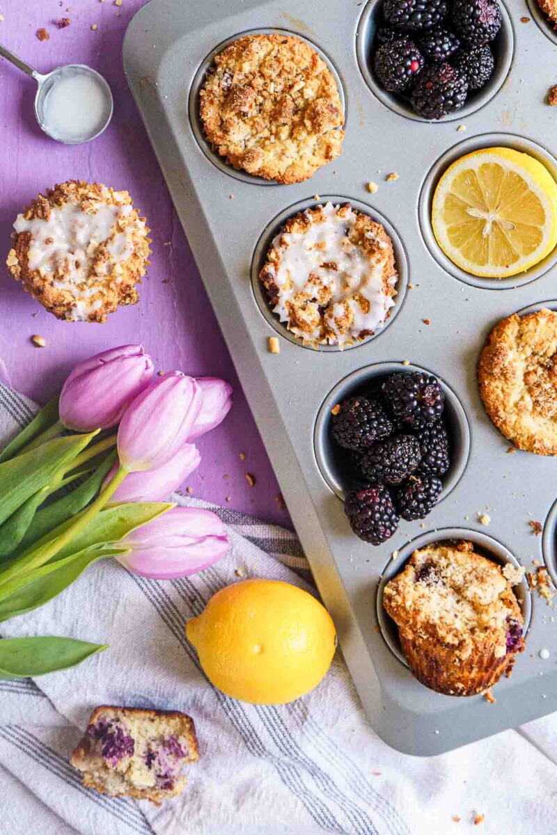 almond flour muffins in tin with bowl of blackberries.