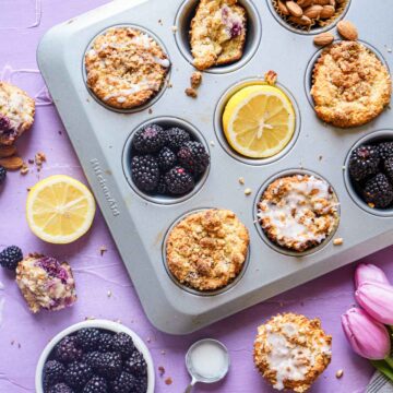almond flour muffins in tin with bowl of blackberries.