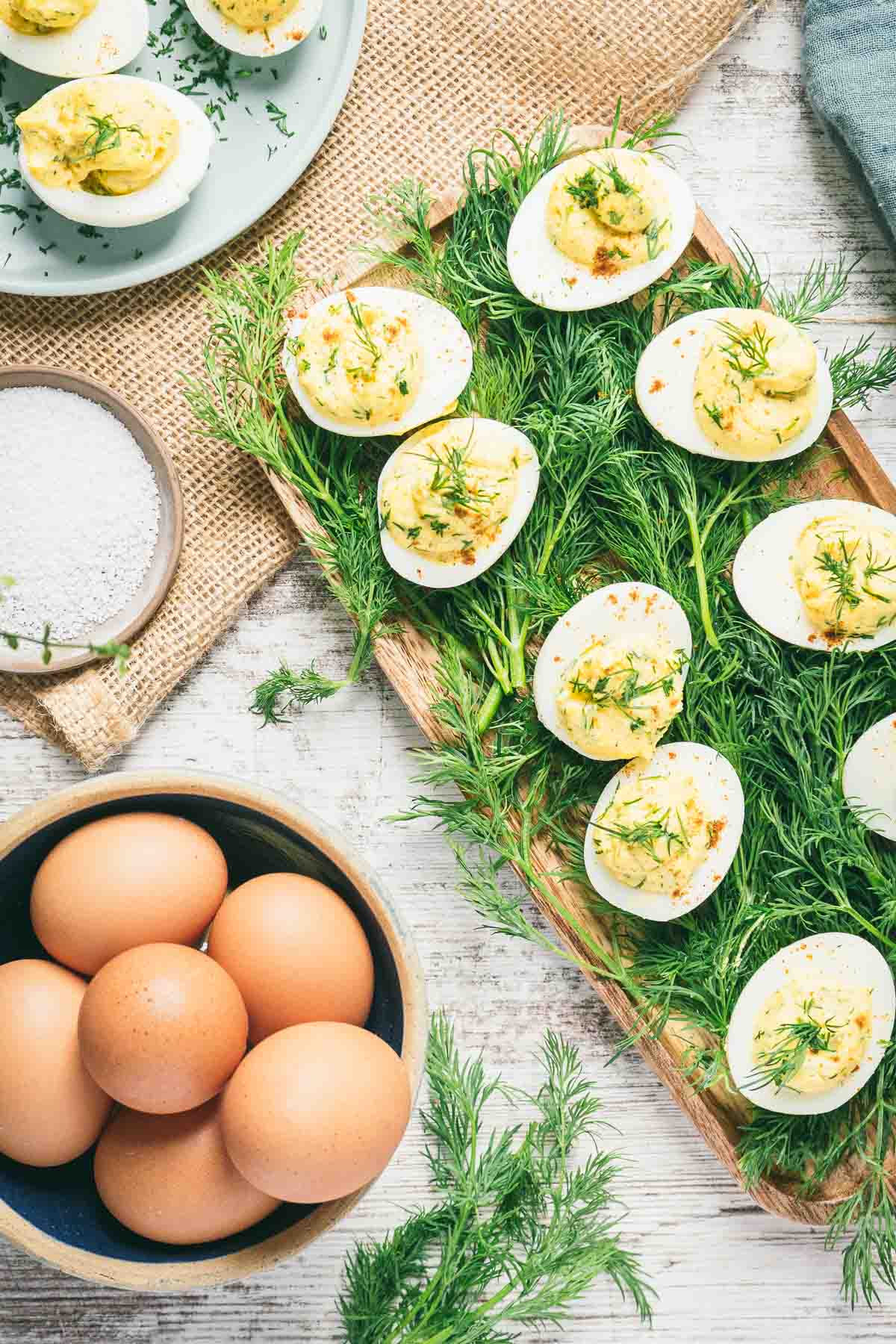 deviled eggs on bed or dill with basket of eggs to the side. 