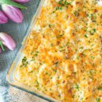 scalloped potatoes in a casserole dish with tulips to the side.