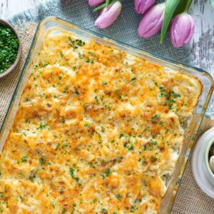 gluten-free scalloped potatoes with cheesy topping in casserole dish.