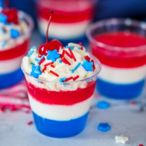 red white and blue layered jello shot with whipped cream and a cherry