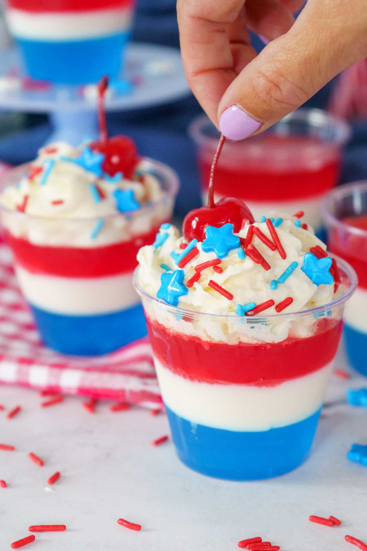 red white and blue layered jello shot with whipped cream and a cherry