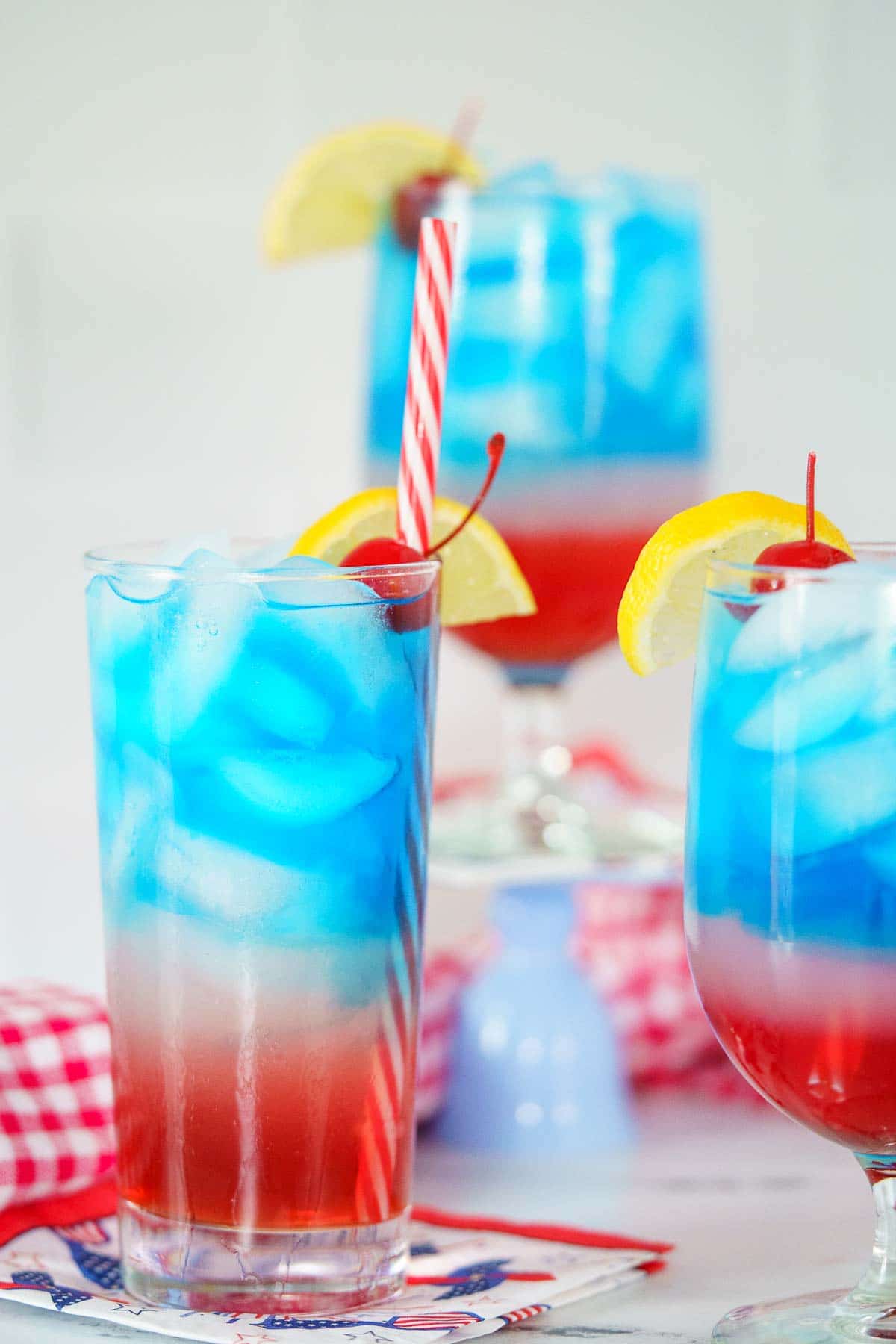 3 red white and blue cocktails on a marble counter
