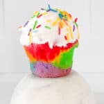 rainbow cupcake with white frosting and sprinkles