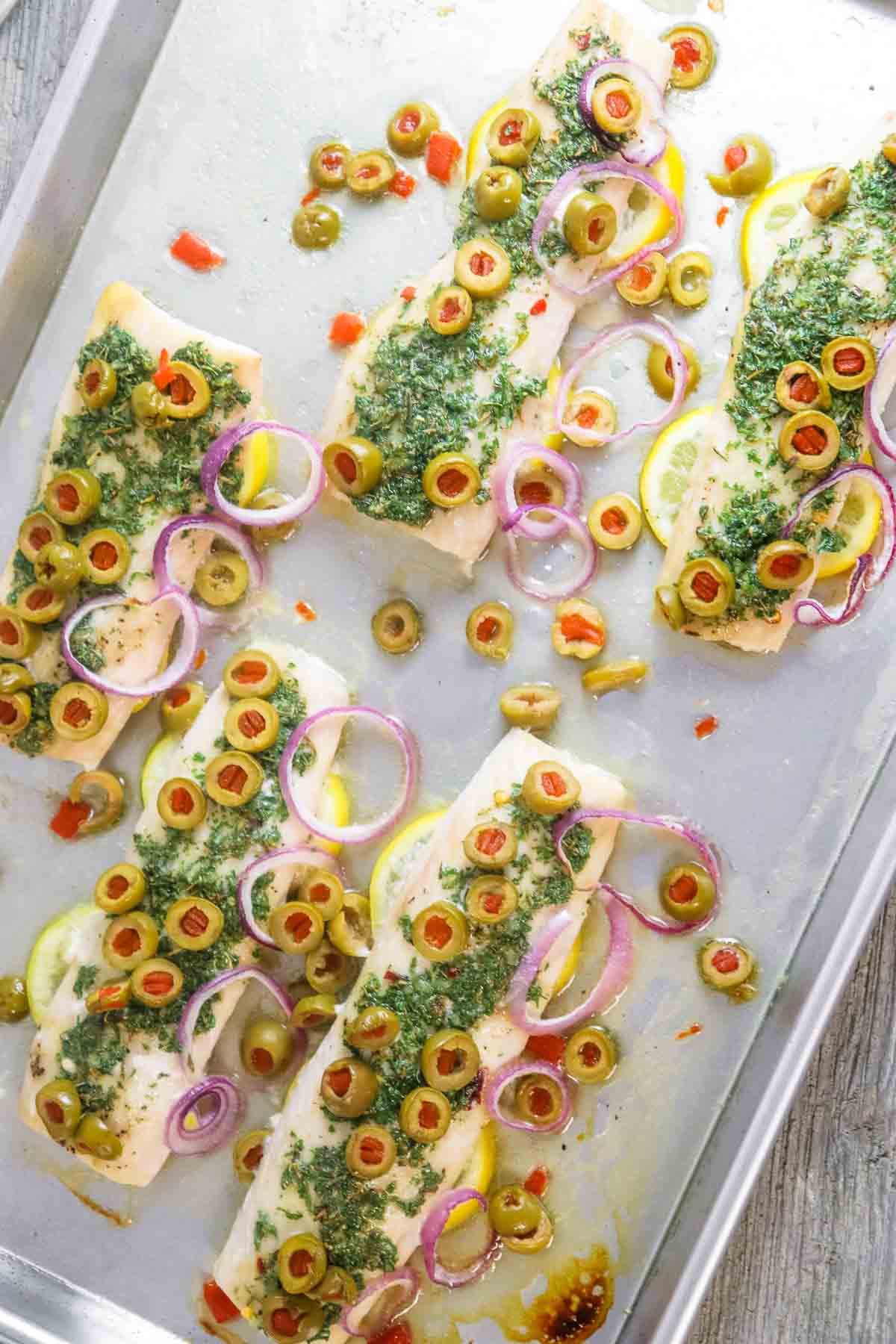 baked mahi fillets with olives and onion on a sheet pan