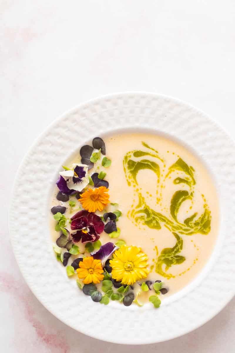 peach soup in a bowl with basil and flowers