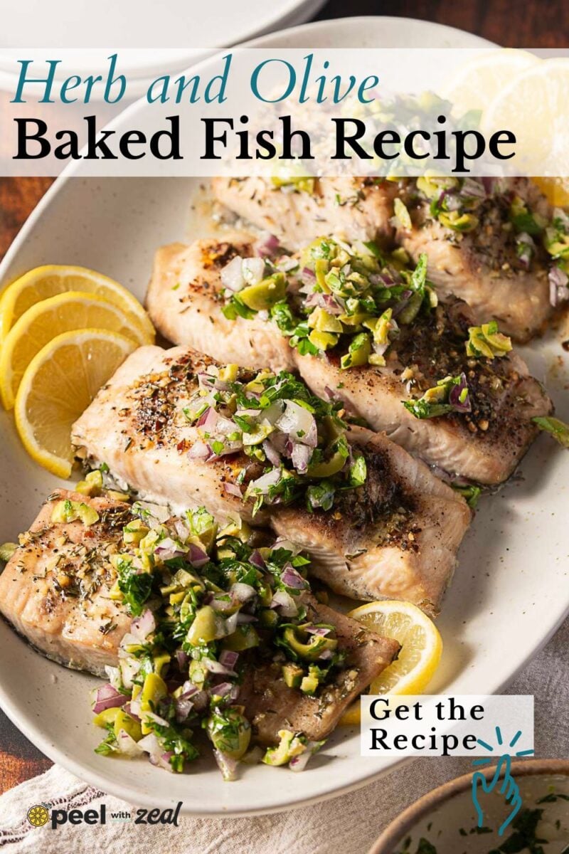 Plated baked mahi mahi fillets topped with chopped herbs, olives, and onions, garnished with lemon slices on a white dish—an elegant baked mahi mahi recipe perfect for any occasion.