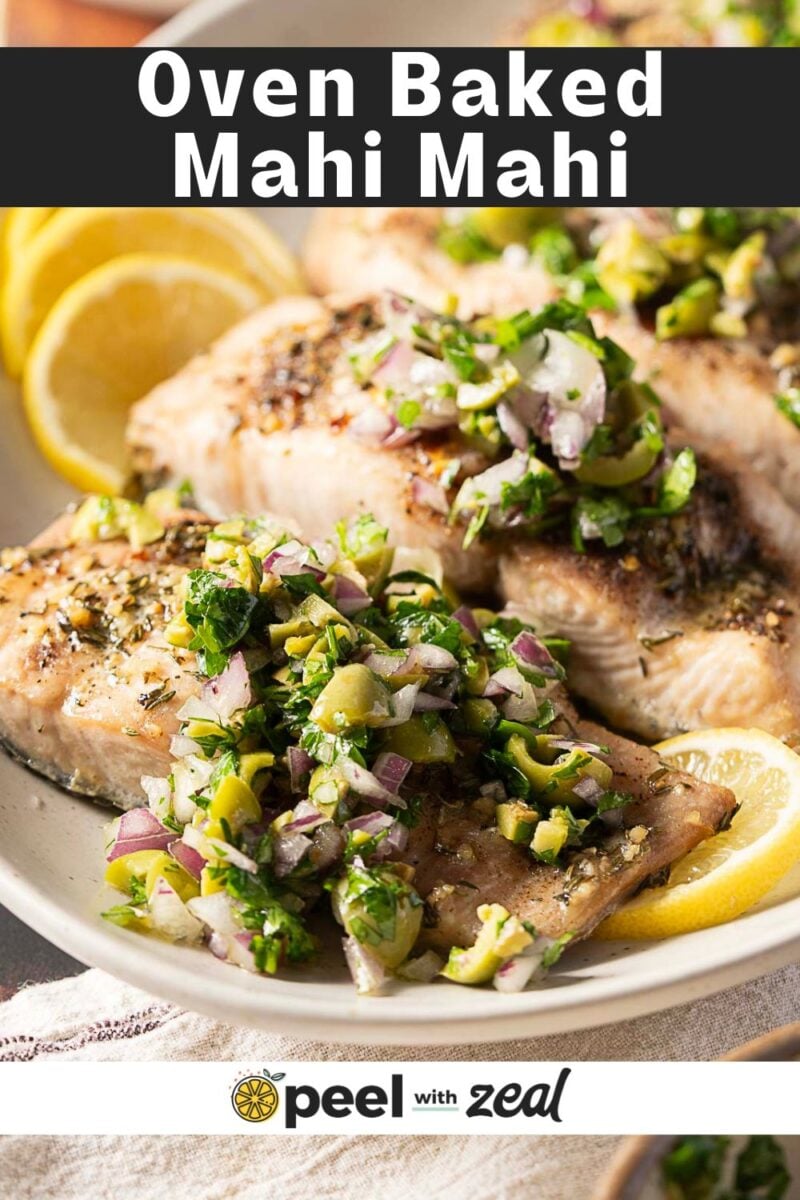 Plate of oven baked mahi mahi fillets topped with a mixture of chopped green olives, red onion, and herbs, garnished with lemon slices—an easy baked mahi mahi recipe perfect for any dinner table.