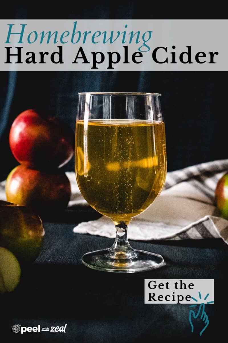 A glass of hard apple cider sits on a table surrounded by apples, with text highlighting an easy hard cider recipe perfect for homebrewing enthusiasts.