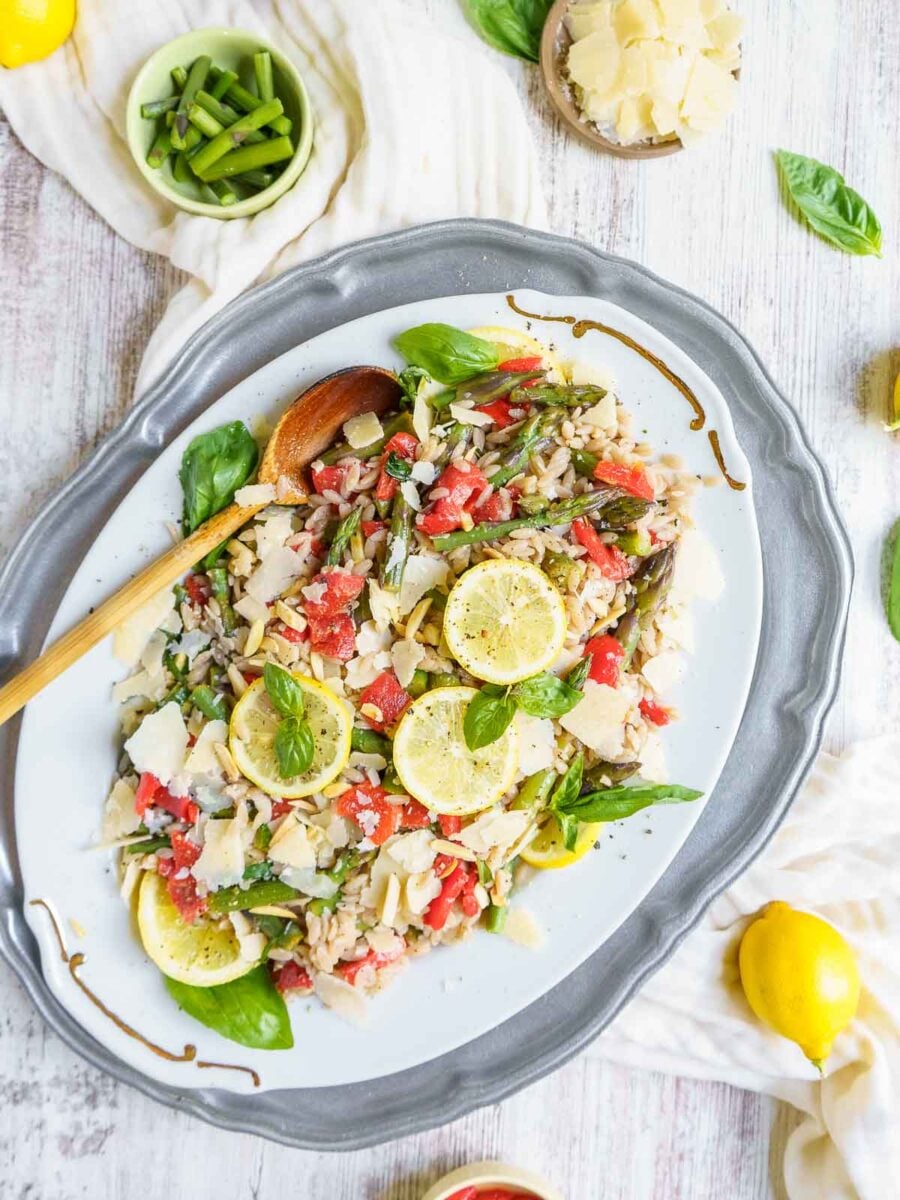 orzo salad on a platter with wooden serving spoon