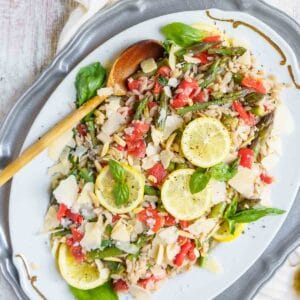 lemon orzo salad on a platter with wooden spoon