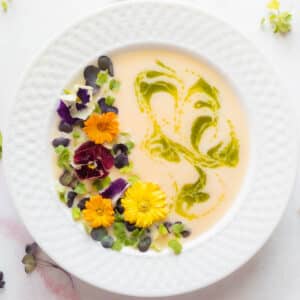 peach soup in a bowl with basil and flowers