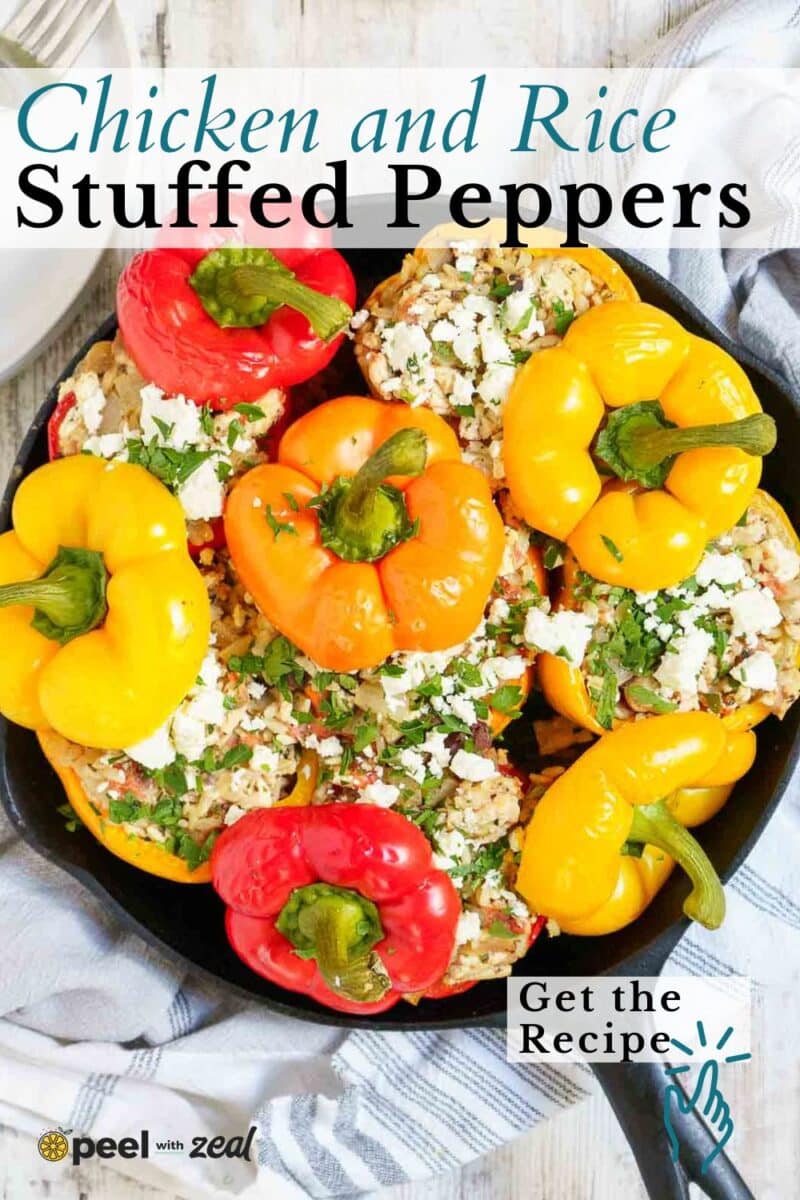 A skillet filled with ground chicken stuffed peppers, featuring red and yellow bell peppers packed with a savory chicken and rice mixture, then topped with crumbled cheese and fresh herbs.