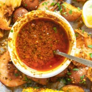 Cajun butter sauce in a white bowl on serving platter with a seafood boil.