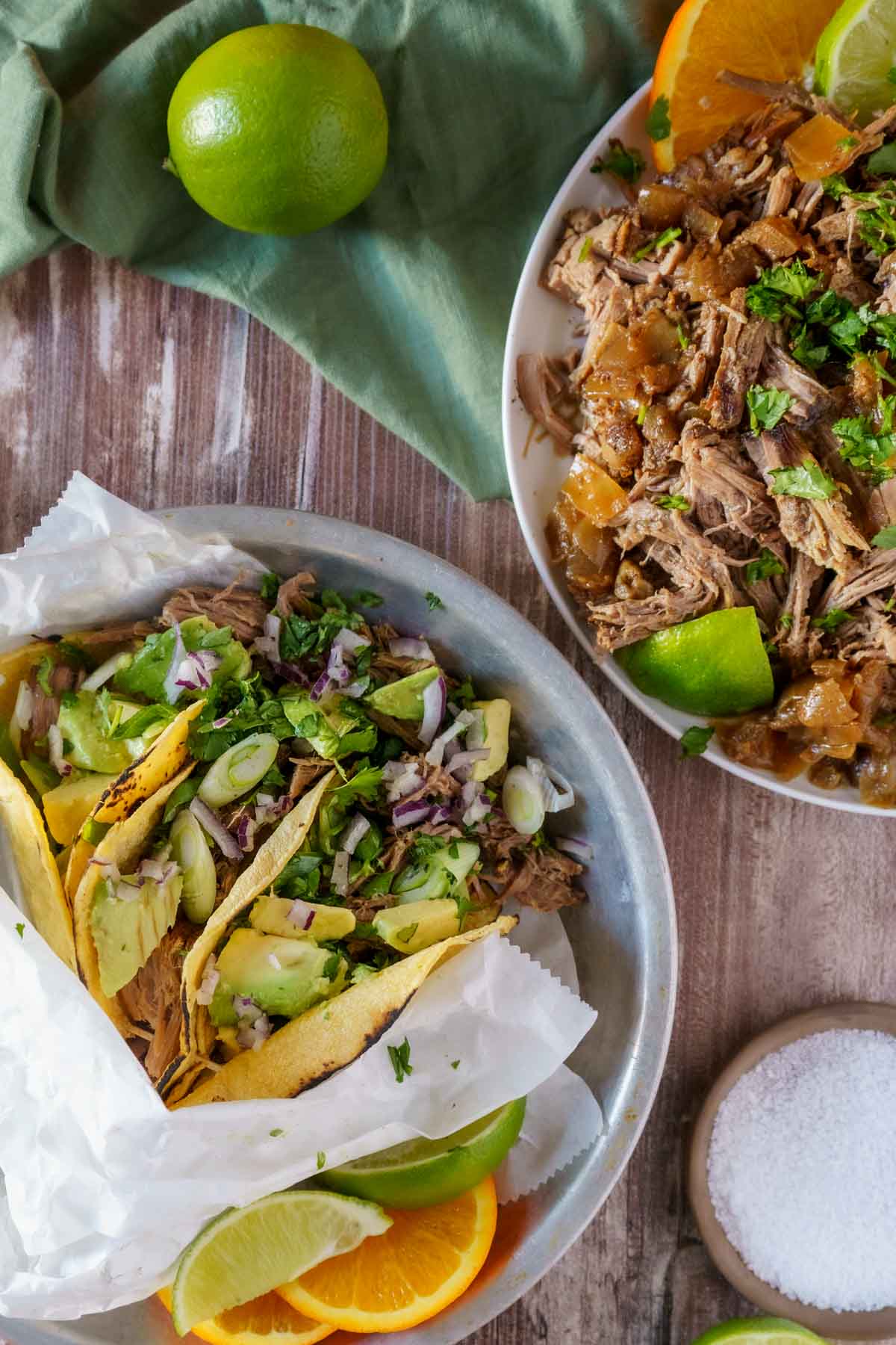 Shredded beef tacos in corn tortillas with avocado and green onions.