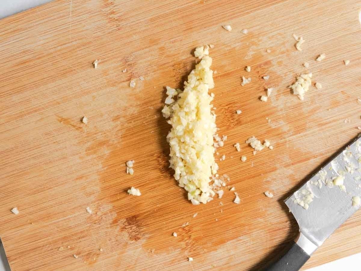 A cloves of garlic on a cutting board, ready to be minced and added to a rich garlic butter sauce.