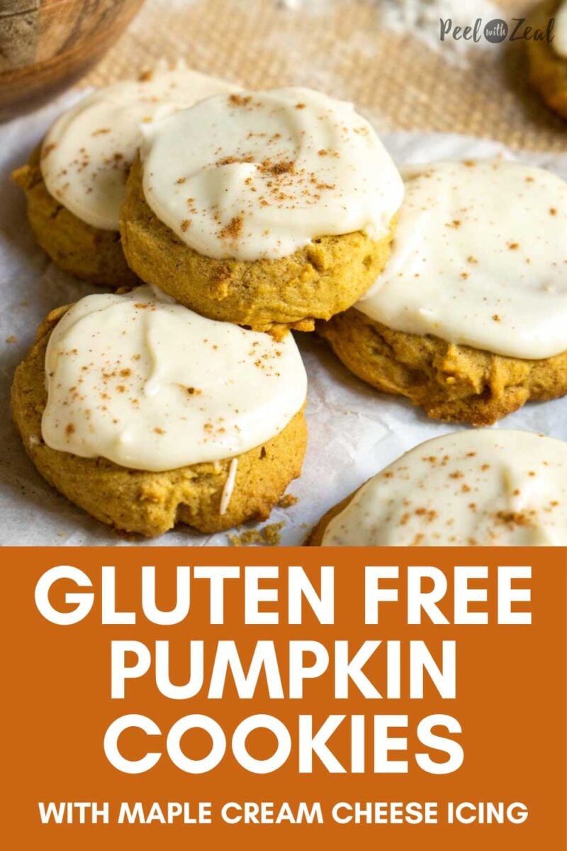 Pumpkin cookies with icing and spices stacked on counter.