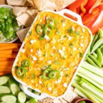 Buffalo chicken dip baked in a white dish. Served with crackers and veggies.