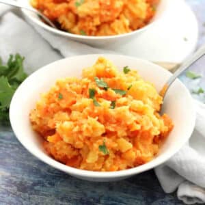 Mashed rutabaga and carrots in a while bowl.
