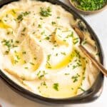 Celeriac puree in a brown bowl with a small bowl of green chives.