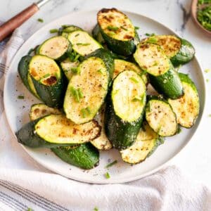 Sliced zucchini, roasted and served on plate with chives.