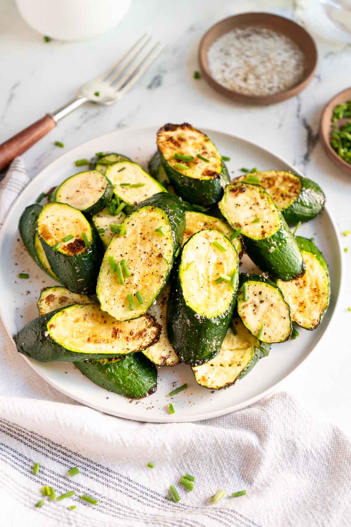 Roasted zucchini on a plate with napkin and a fork.