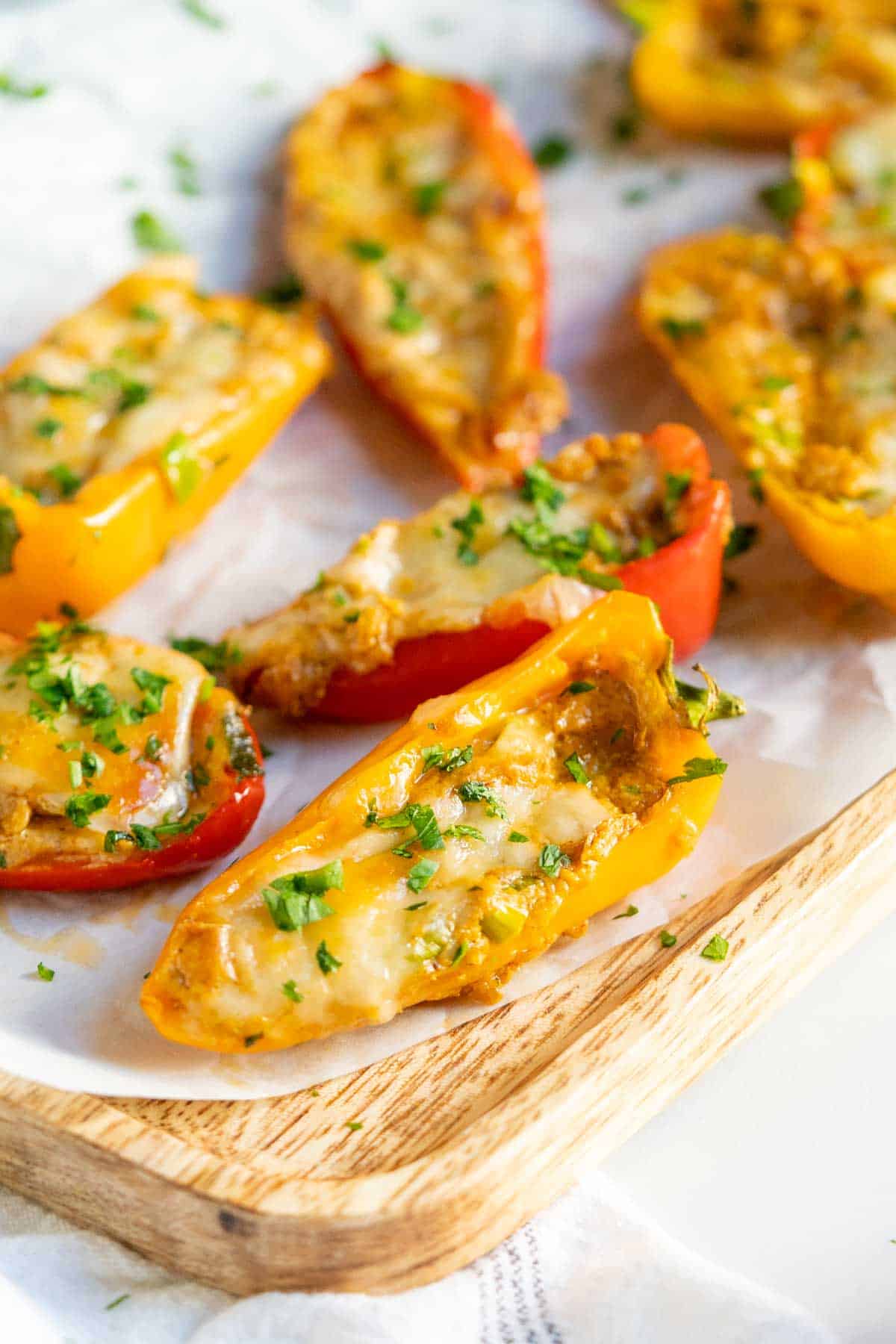 Cream cheese stuffed peppers on a wooden serving board.