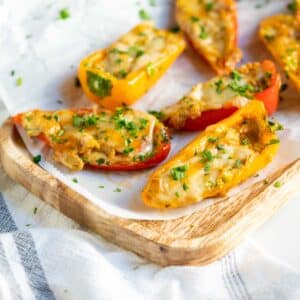 Cream cheese stuffed peppers on a wooden serving board.