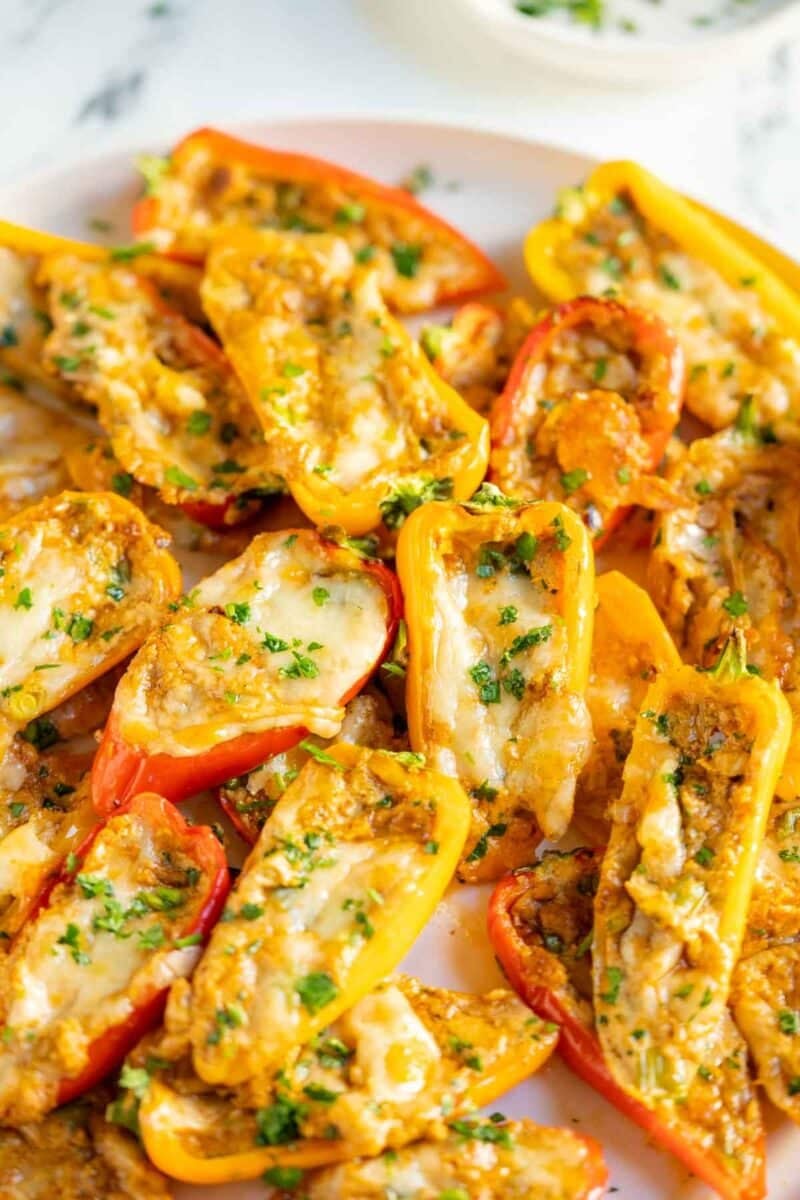 Cream cheese stuffed peppers on a white plate and topped with parsley.