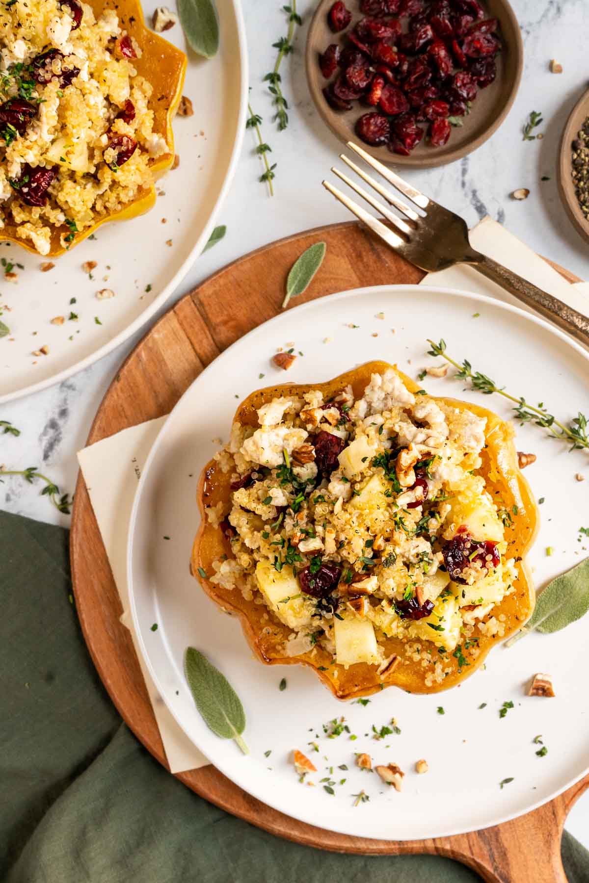 Ground turkey, quinoa, and cranberries stuffed in a squash on a white plate with sage leaves.