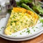 Slice of quiche on a plate with a green salad.