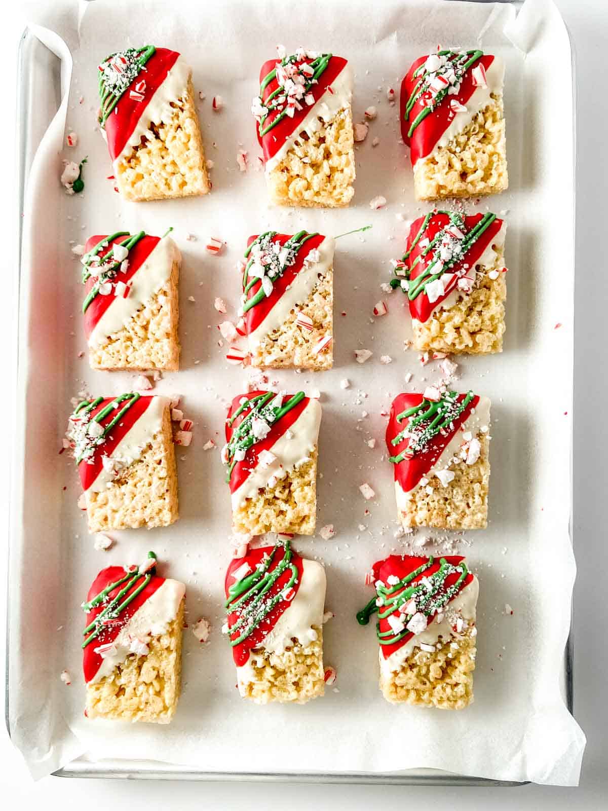 Rice cereal treats decorated with red and green on a baking sheet.