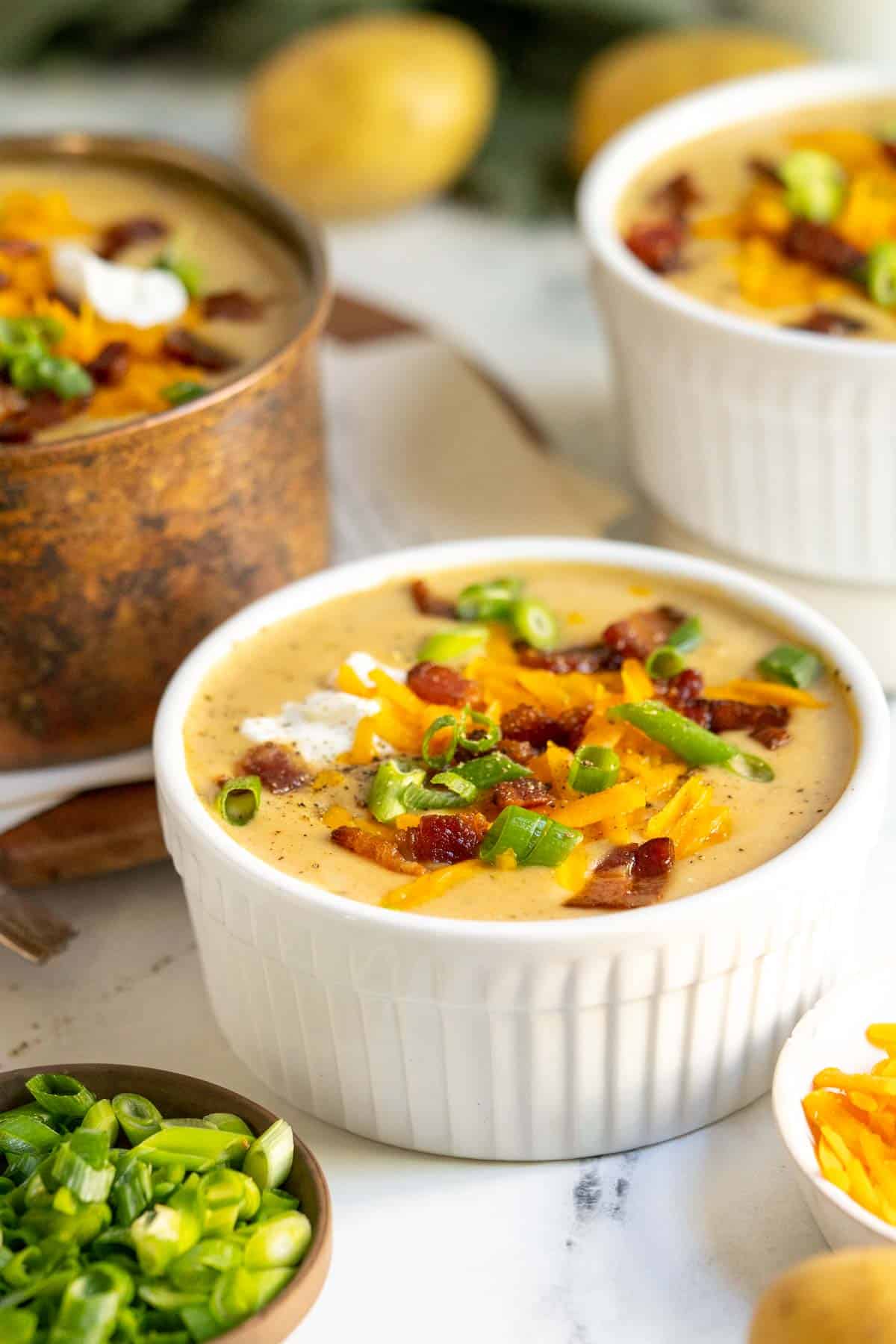 Potato soup in white bowl with bacon and cheese.