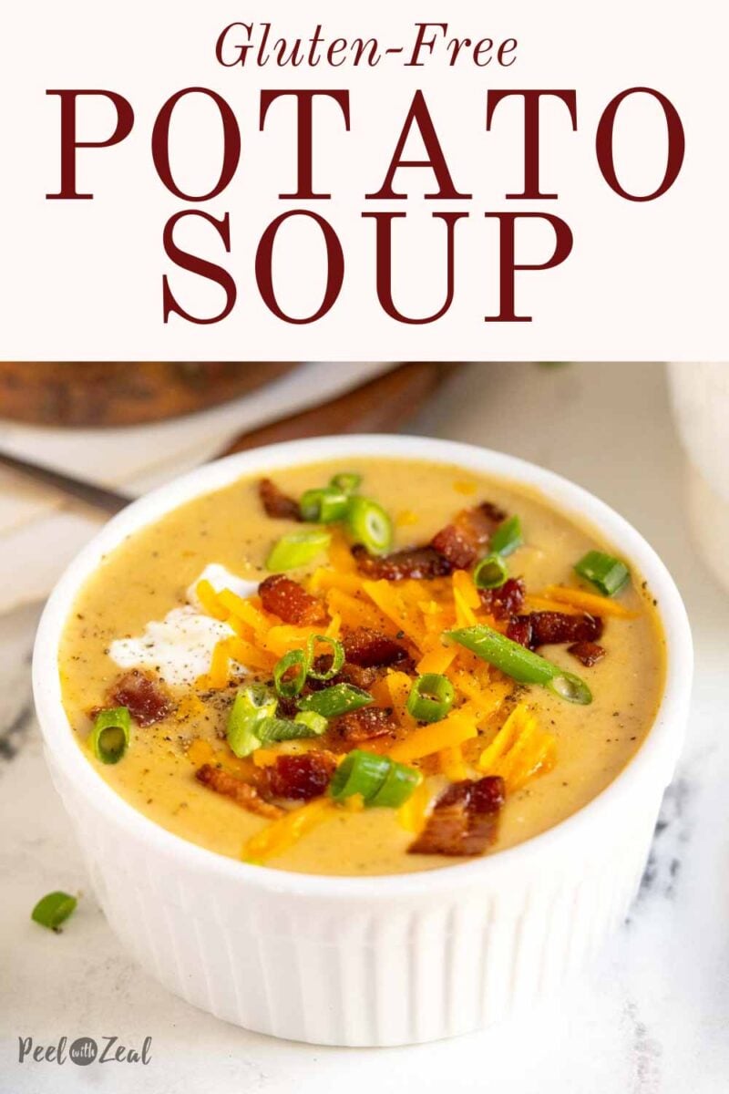 Potato soup in white bowl with bacon and cheese.