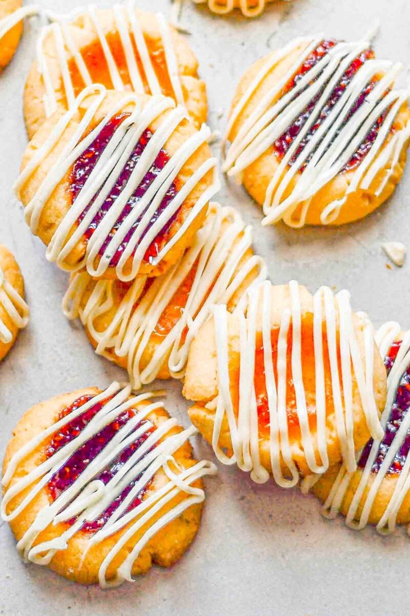 Jam filled thumbprint cookies on a baking sheet.